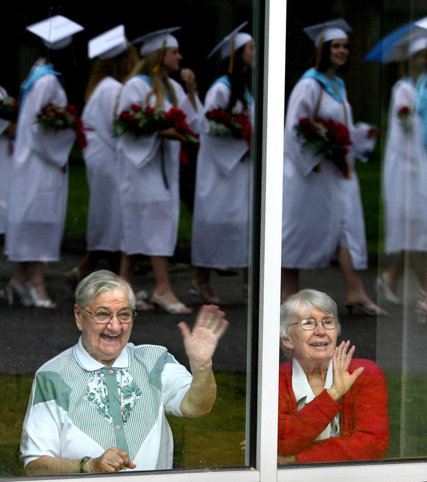 First Place, Photographer of the Year - Lisa DeJong / The Plain DealerSister Mary Fatima Adams, 82, left, and Sister Eileen Duffy, 84,  wave at the senior girls during the "Walk of the Roses", an annual procession from St. Joseph Academy to their commencement ceremony at Our Lady of Angels church.  "It's always a beautiful sight to me," said Sister Eileen. "They look so beautiful in their white gowns and red roses. It's the hope of the future."  Sister Eileen graduated from St. Joseph Academy in 1941 and Sister Mary Fatima graduated from the school in 1948. 