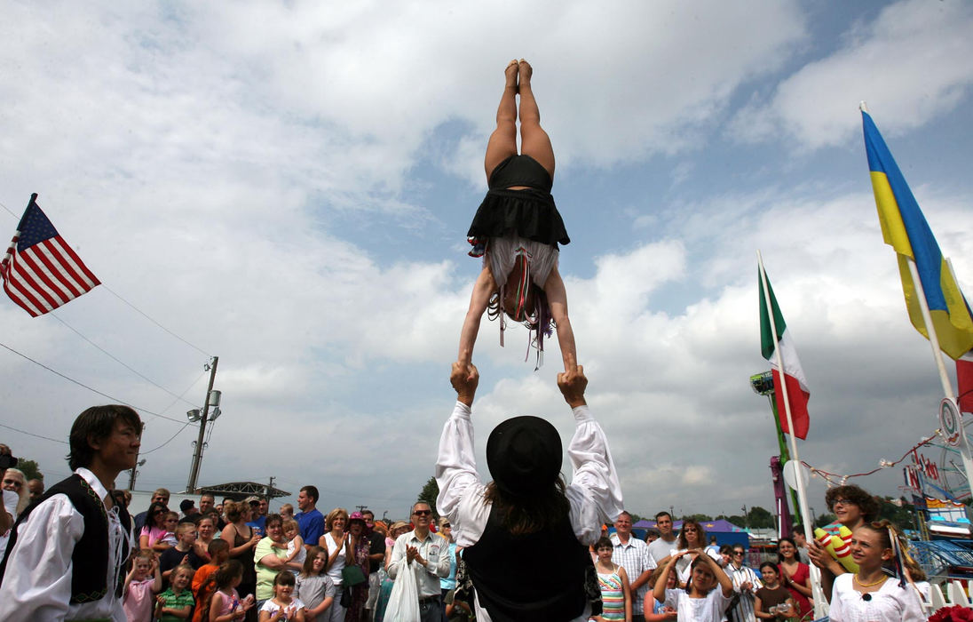 First Place, Photographer of the Year - Lisa DeJong / The Plain DealerGiovanni Zoppe balances aerialist Amy Riccio in front of a gathered crowd hoping to sell tickets to their circus at the Italian American Festival during a stop in Canton.