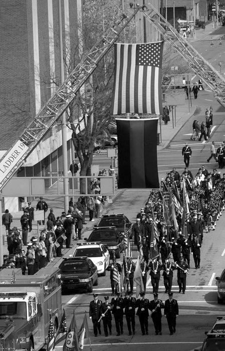 Second Place, Photographer of the Year - Michael E. Keating / Cincinnati EnquirerFlag carrying first responders and the symbolic ladder truck salute with a two tone flag and a US flag notes the passing of two firefighters.