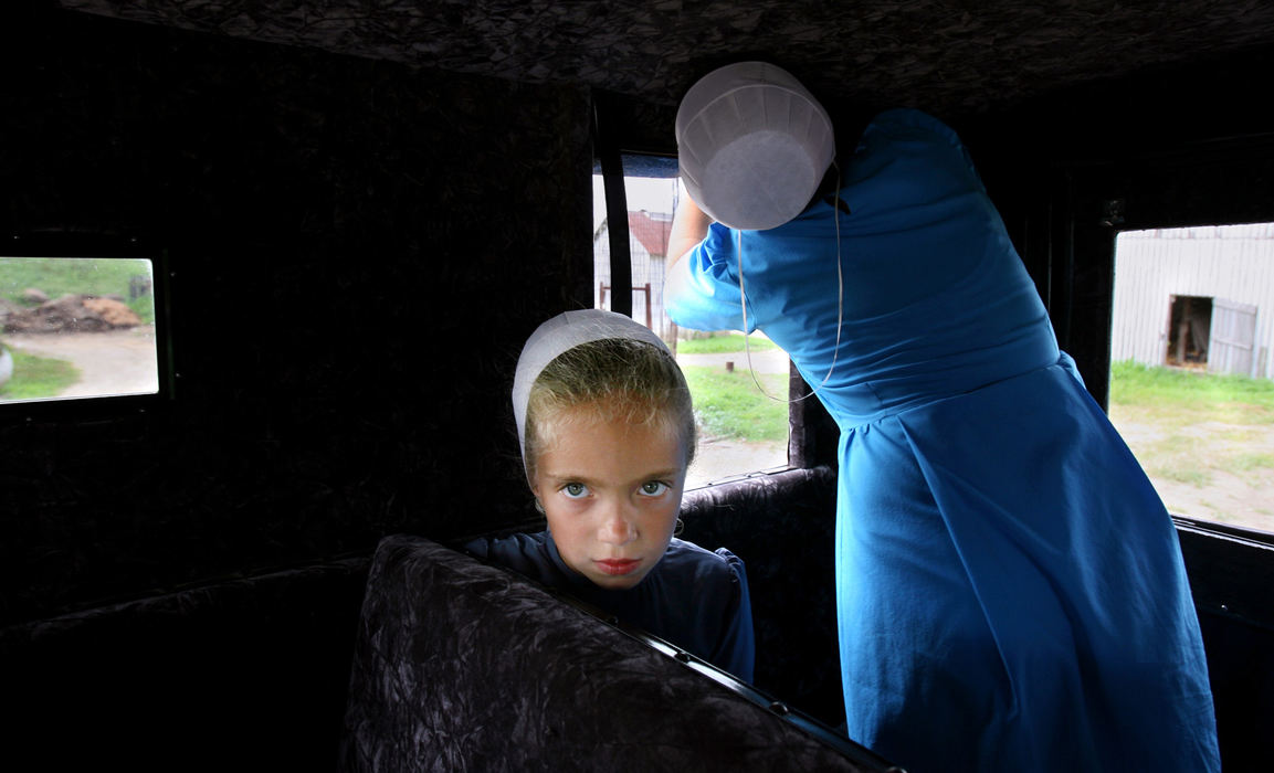 Third Place, Photographer of the Year - Gus Chan / The Plain DealerRamanda Yoder, 6, sits in the back of her uncle's buggy as her cousin, Krista Miller, 12, pulls back the blinds on the buggy.  Ramanda was headed to Mt. Hope to be picked up by her father.  