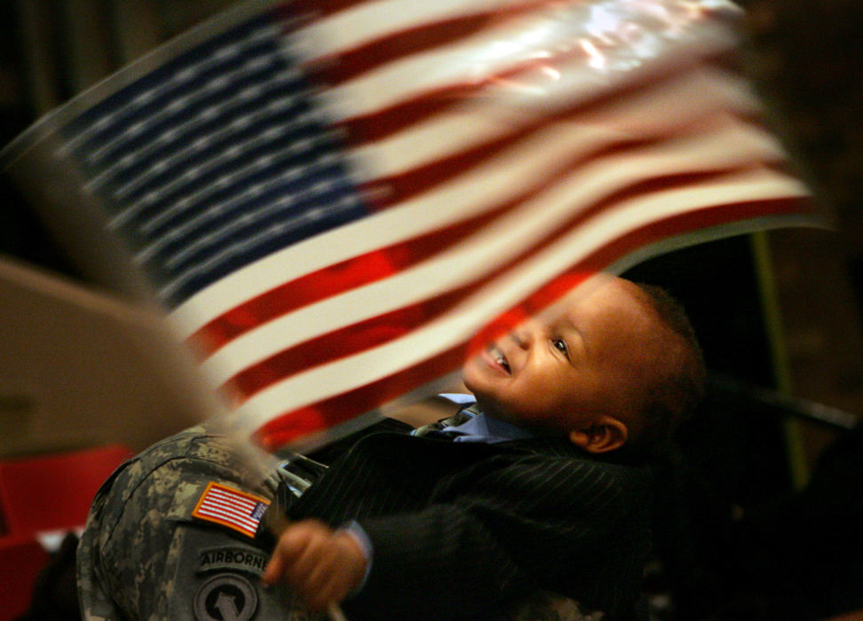 Third Place, Photographer of the Year - Gus Chan / The Plain DealerJoseph Ferrell, 14 months, of Cleveland, waves the American flag while in the arms of his father, Staff Sergeant Jeffrey Ferrell during the return of the 237th  Support Battalion.  The battalion was honored in a welcome home ceremony at the Canton Memorial Civic Center.    