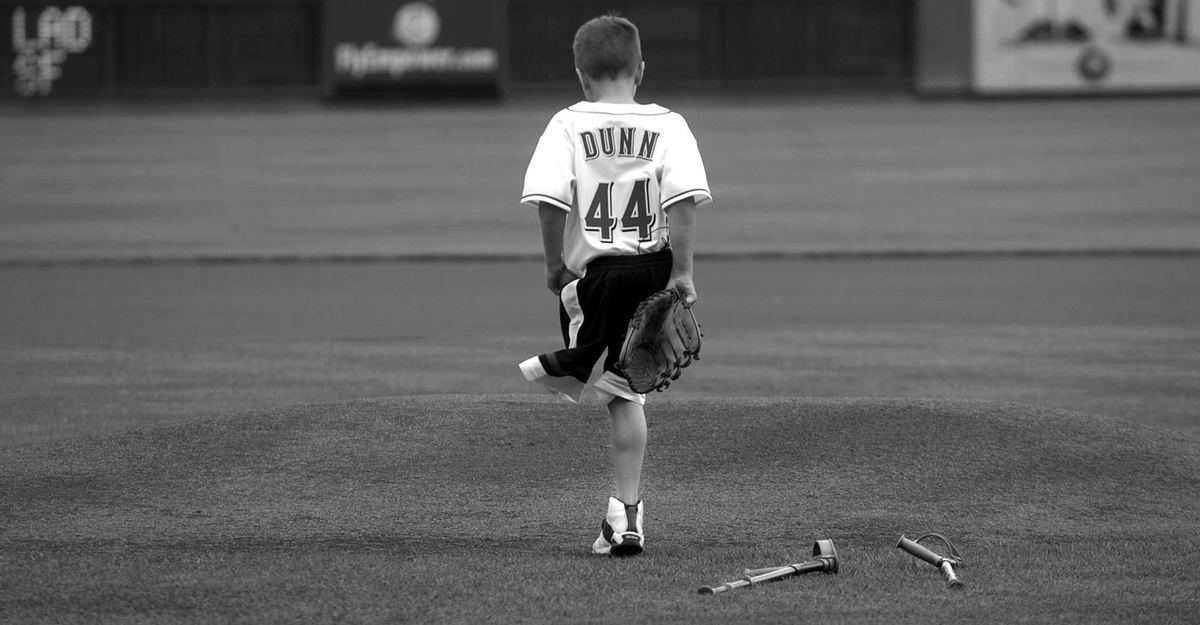 Award of Excellence, Sports Feature - Michael E. Keating / Cincinnati EnquirerEight year-old Adam Bender drops his crutches and hops on to the pitchers mound to deliver the first pitch.  Bender lost his leg to cancer as a one year-old, but still plays baseball in his hometown of Lexington, Ky.. 