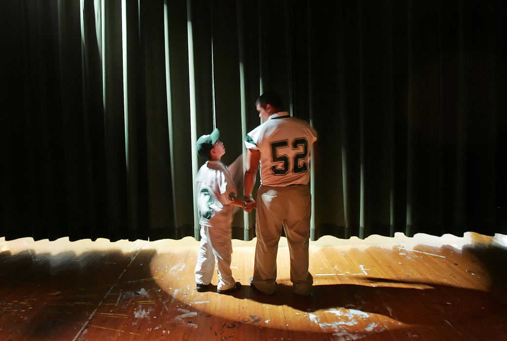 Award of Excellence, Sports Feature - John Kuntz / The Plain DealerJon Lopez (right) a football player with Holy Name in Parma Heights holds the hand of Chris Buzinski,12, backstage before the curtain is drawn and Chris is introduced as one of the team's captains September 19, 2008.  Chris has cerebral palsy and was able to spend the day going to classes with the football players before their final game of the season where Chris will participate in. 