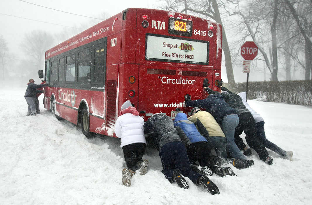 Second Place, Spot News over 100,000 - Lisa DeJong / The Plain DealerSome good samaritans spent about 45 minutes helping the RTA Circulator bus slowly spin his way down Overlook Road in Cleveland Heights during a huge snowstorm on March 8, 2008. The bus pushers, all neighbors, some who have never even met before, said they were out for hours helping snowed-in motorists dig out, one after another. They helped about 15 cars get unstuck.  With hoops and cheers, the crowd finally pushed the bus on it's way down Euclid Heights Blvd.
