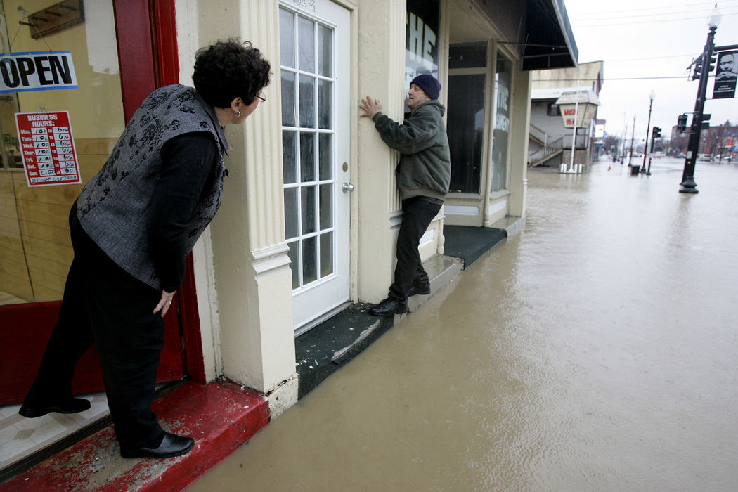 Award of Excellence, Spot News over 100,000 - Dave Zapotosky / The Blade Christina Bennett, owner of Beauty Salon 2003, 132 N. Main St., Findlay, watches as Vincent May of Findlay tries to avoid stepping in flood water on N. Main St., in Findlay, Ohio, on February 6, 2008.  Bennett had closed her shop due to the flooding. 