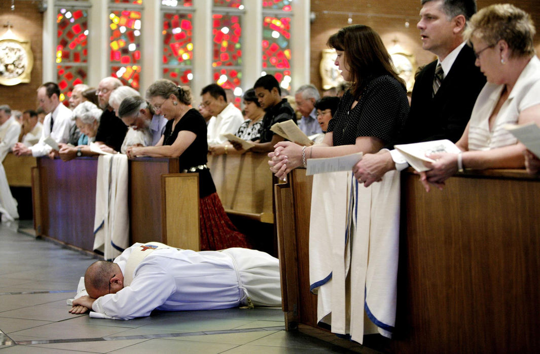 First Place, Feature Picture Story - Fred Squillante / The Columbus DispatchRobert Bolding lays on the floor of Saints Simon and Jude Cathedral as part of the ceremony during his ordination to the priesthood, in Phoenix, Arizona. In the pew at right are (from left) his mom, Patty, dad, Al, and grandmother Sue Schepers.