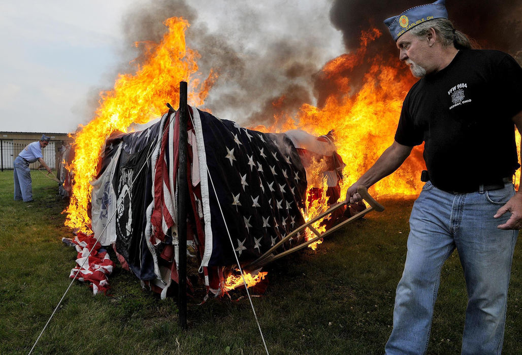 Award of Excellence, General News - Marshall Gorby / Springfield News-SunJerome Petry (right) helps to sets fire to over 7,000 flags behind Legion Post 286 in New Carlisle during an official ceremony to retire worn and unusable flags on Flag Day on June 14, 2009. 