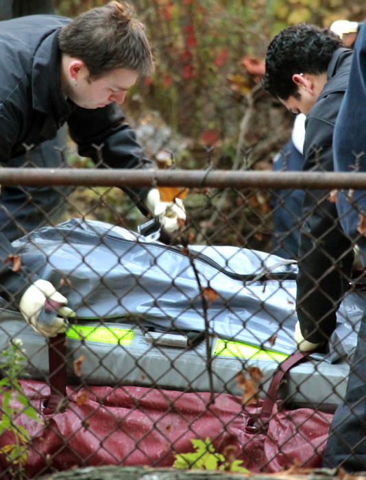 Second Place, News Picture Story - John Kuntz / The Plain DealerCuyahoga County coroners fasten straps around a body dug up from the back yard at the home of Anthony Sowell November 3, 2009 in Cleveland's east side. 