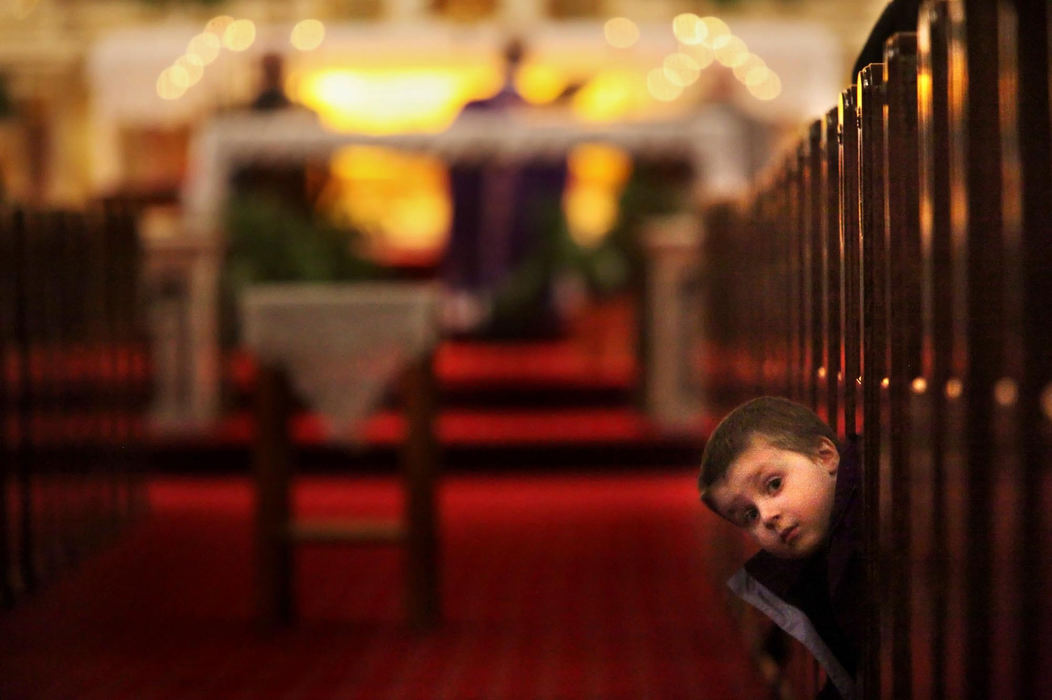 First Place, News Picture Story - Gus Chan / The Plain DealerDaniel Flesza pokes his head out of the pew during the Polish mass at St. Casimir Church.  The church closed it's door for the final time last November.