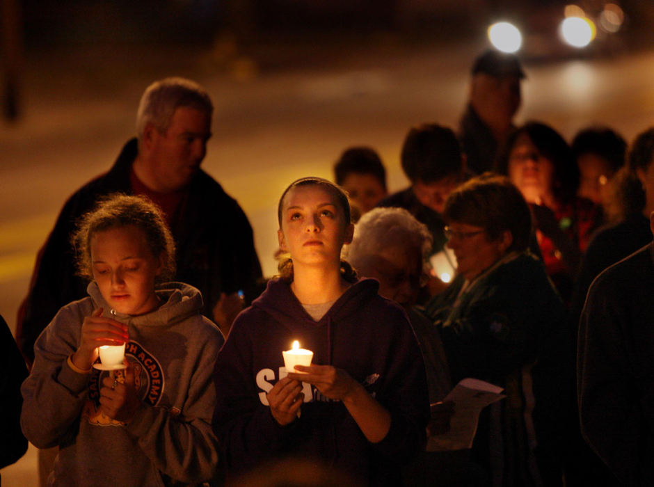 First Place, James R. Gordon Ohio Understanding Award - Gus Chan / The Plain DealerSara Gulasey (center) looks upward as raindrops fall during a candlelight vigil at St. Patrick Church.  Bishop Richard Lennon recently announced the closing of the church.  