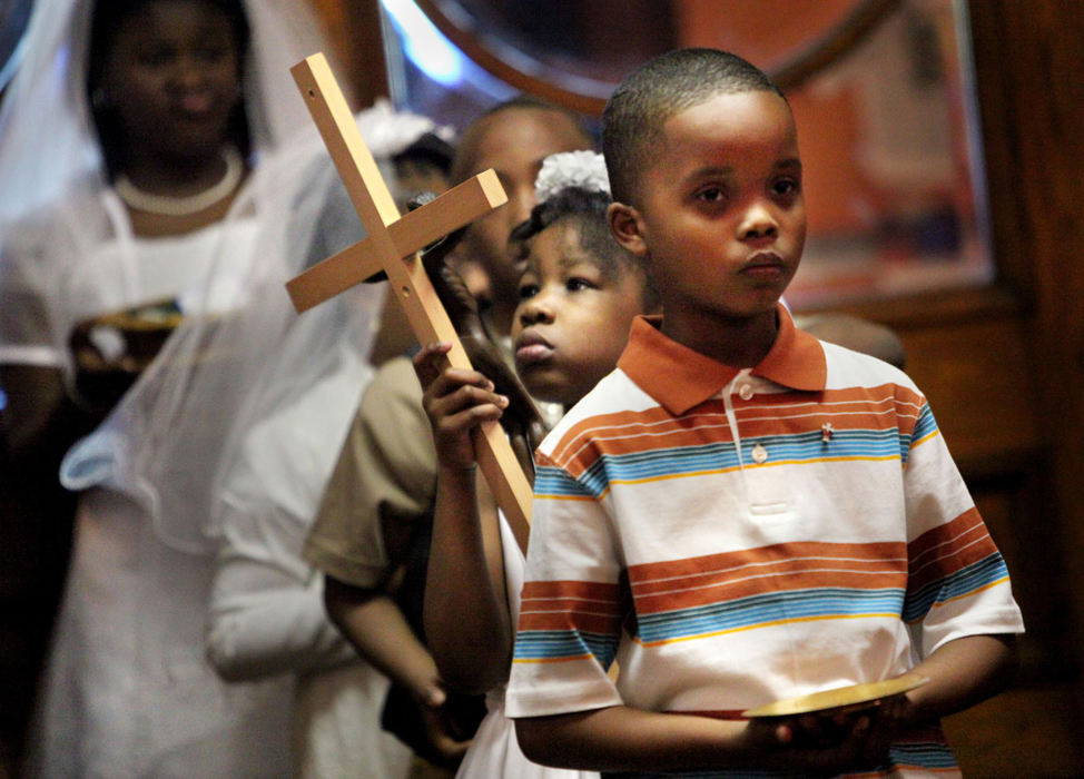 First Place, James R. Gordon Ohio Understanding Award - Gus Chan / The Plain DealerMorgan Slone (left) stares intently at the crucifix as Rudolph Thompson III (right) prepares to lead the  procession for First Communion at St. Adalbert Church.   
