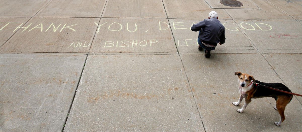 First Place, James R. Gordon Ohio Understanding Award - Gus Chan / The Plain DealerBill Sheehan, a parishioner at St. Colman Church, writes a thank you note to God and Bishop Richard Lennon before the 5 p.m. mass.  Sheehan, with his dog, Bowser, wrote the chalk note after hearing that  Bishop Richard Lennon had rescinded his order to close St. Colman.  