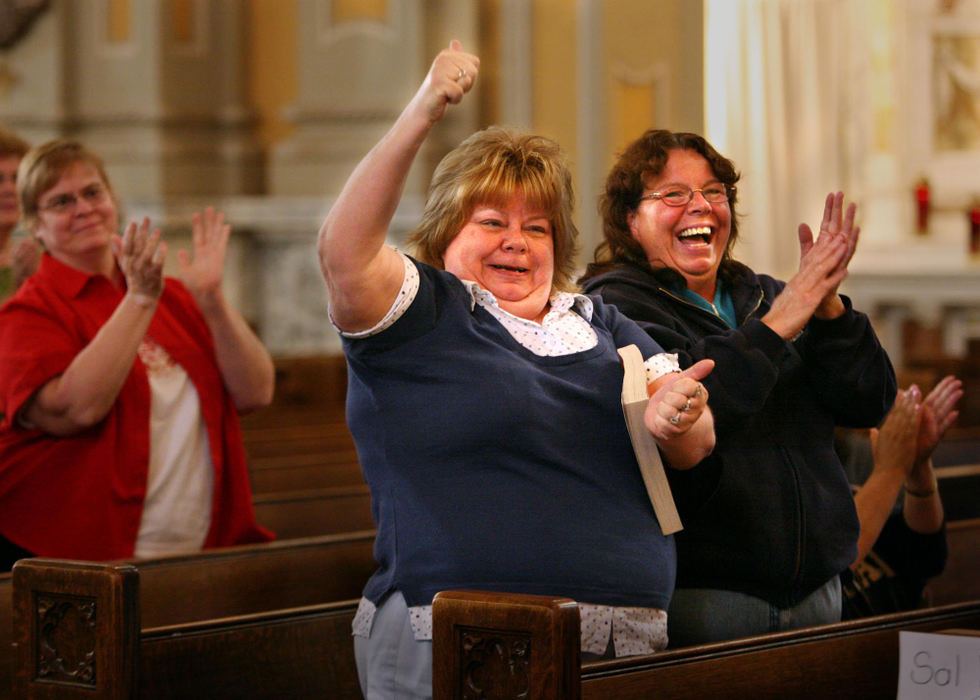 First Place, James R. Gordon Ohio Understanding Award - Gus Chan / The Plain DealerSisters Sue McMasters (center) and Shirley Panagopoulos (right) celebrate the announcement that St. Colman Church will remain open, during mass.  St. Colman will keep it's doors open after Bishop Richard Lennon rescinded his order to close it's doors.  The sisters have been members of the church since 1965.  
