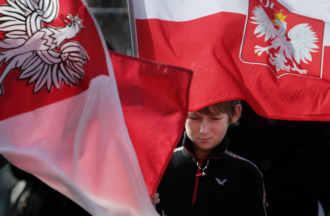 First Place, James R. Gordon Ohio Understanding Award - Gus Chan / The Plain DealerOlek Chmura, 13, of North Royalton, holds the Polish flag outside St. Casimir Church during a morning prayer service.  Parishioners continue to hold prayer services outside the closed church.