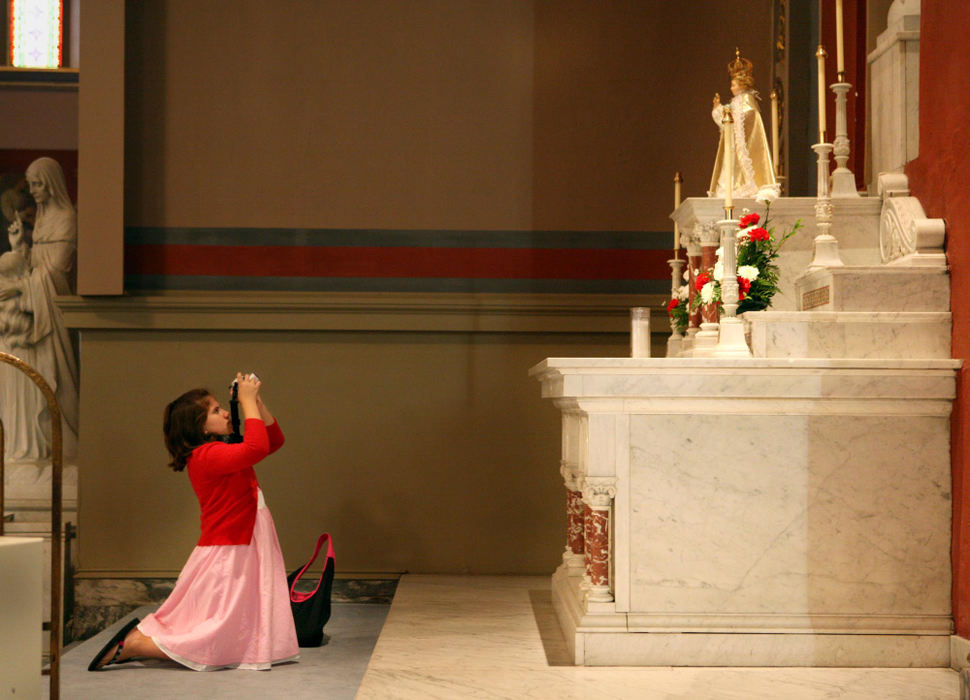 First Place, James R. Gordon Ohio Understanding Award - Gus Chan / The Plain DealerAnnie Holan,, kneels as she takes a picture of the altar after the final mass at St. Procop Church.  The church closed it's doors for the final time after the morning service. 