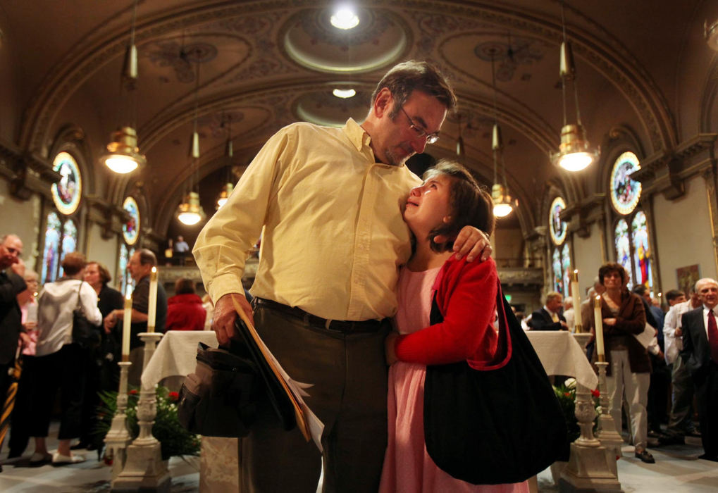 First Place, James R. Gordon Ohio Understanding Award - Gus Chan / The Plain DealerMark Holan (left) comforts his daughter, Annie,  as the two were standing on the altar after the final mass at St. Procop Church.  The church closed it's doors for the final time after the morning service. 