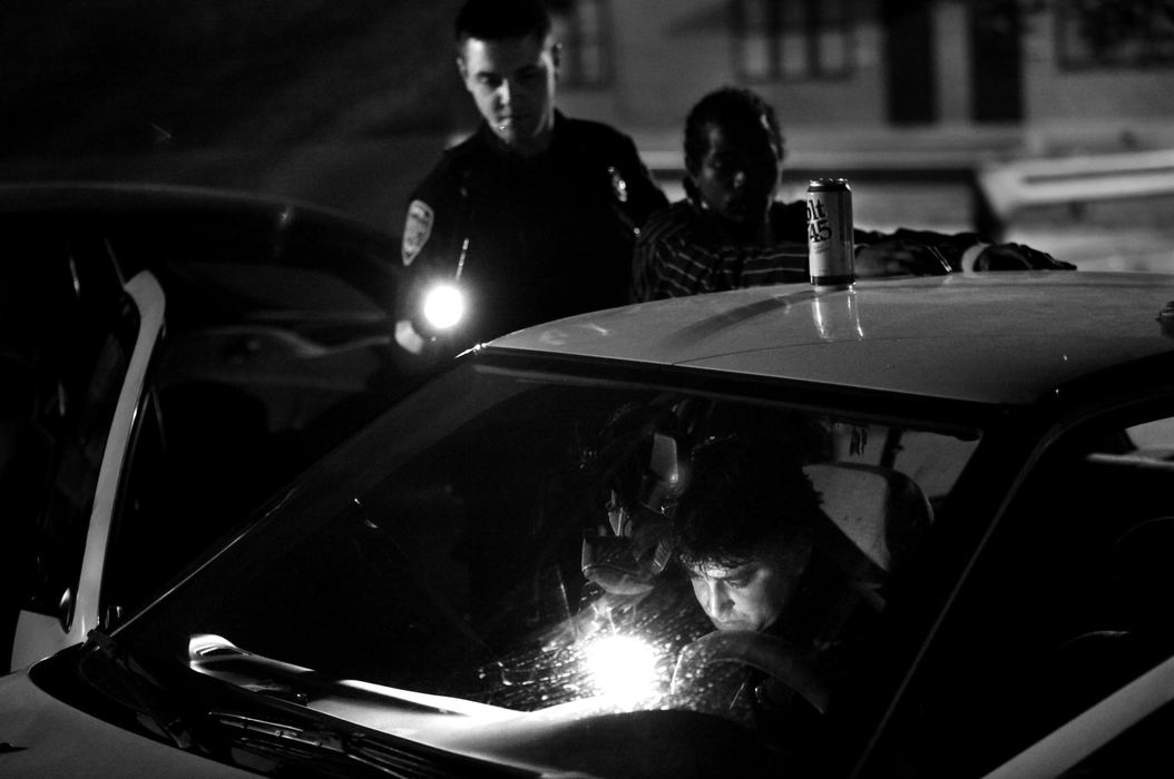 Second Place, Photographer of the Year Large Market - Gus Chan / The Plain DealerCuyahoga Metro Housing Authority police officer Clint Ovalle searches a car for drugs after the driver and a passenger were stopped for having open containers at CMHA's Woodhill Estates.