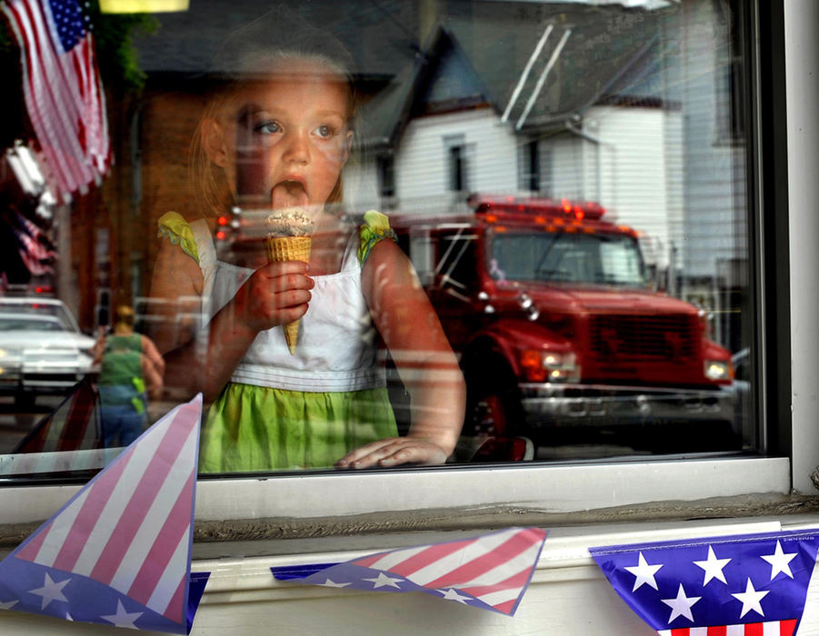First Place, Photographer of the Year Small Market - Bill Lackey / Springfield News-SunA Memorial Day Parade is reflected in the front window of the Catawba Store in Catawba, May 24, 2009 as Madeleine Taylor, 3, watches the parade through the window while eating her ice cream cone. 