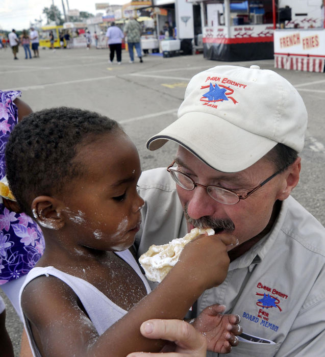 First Place, Photographer of the Year Small Market - Bill Lackey / Springfield News-SunNadir Langston, 3, shares his sugar waffle, minus some powdered sugar, with Clark County Fair Board member John Maurer on the fair's midway. Maurer, a longtime member of the fair board, is retiring after this year's fair.  