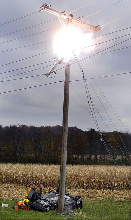 First Place, Photographer of the Year Small Market - Bill Lackey / Springfield News-SunUrbana firefighters, attempting to rescue the driver of an overturned car that struck a utility pole, look up at the arcing wires that are exploding above them Oct. 28, 2009 along Ohio 68 in Champaign County. Part of the pole broke when the car struck it causing the charged wires to arc and catch fire.  