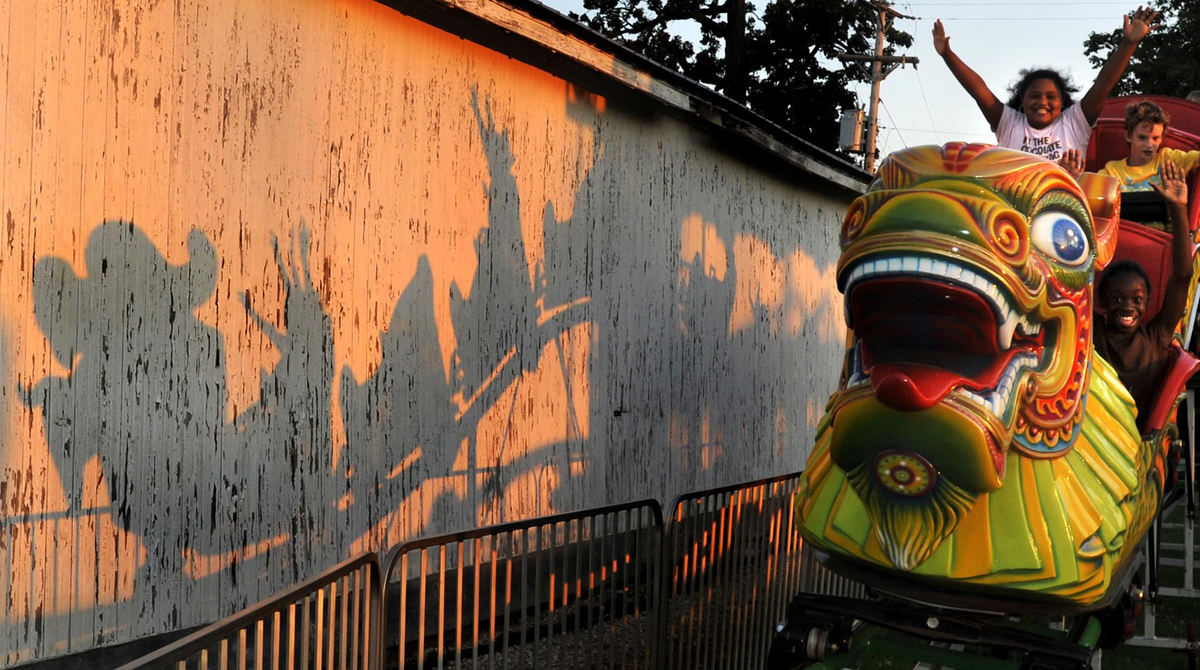 First Place, Photographer of the Year Small Market - Bill Lackey / Springfield News-SunThe shadows of riders on the "Orient Express" ride at the Champaign County Fair in Urbana are cast on a white washed building behind the ride as they hold their hands up in the warm evening sunlight, August 13 2009. 