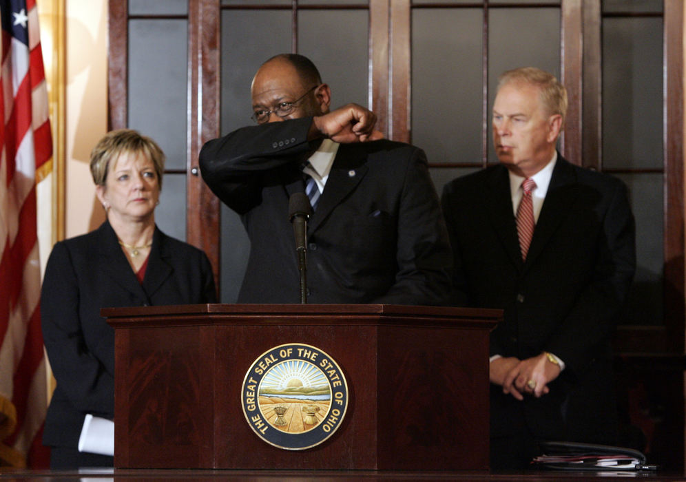 Second Place, Team Picture Story - Tom Dodge / The Columbus DispatchSuperintendent Deb Delisle (left) with Dr. Alvin Jackson, center, Director of Ohio Dept. of Health and Governor Ted Strickland, right, during a H1N1 briefing in the Governor's Cabinet room October 7, 2009.  Dr. Jackson is demonstrating the cough-in-your-elbow technique.