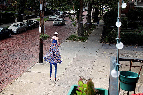 Second Place, Feature - Lisa DeJong / The Plain DealerStiltwalker Julia Pankhurst makes her way down Murray Hill Road, practicing her stilt walking. Pankhurst, who has walked on stilts for years, says that these particular stilts make her about ten feet tall. Pankhurst is seen often at local parades. 