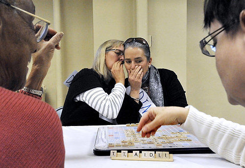 Third Place, Feature - Bill Lackey / Springfield News-SunMary Jo Groves, left, whispers to her sister, Joyce Shaw as they play Mable Jackson, left, and Vicki Lindsay in a heated game of Scrabble during the Scrabble Scramble and Silent Auction for Literacy hosted by the Altrusa International Club of Springfield. 
