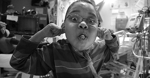 Third Place, Feature picture story - Michael E. Keating / MIchael E. KeatingMaking faces is a favorite pasttime for Manny Evans. Manny Evans, 7, has lived five of his seven years as a resident of Cincinnati Children's Hospital Medical Center.  Diagnosed with neurofibromatosis the genetic disorder that forms tumors that surround nerves, Manny  requires medical and nursing care beyond what can be provided in a residential environment.  His mother chooses to let him live at the hospital instead of a residential center or nursing home.  Manny recently began his schooling at Roselawn Condon School and a school bus picks him up each day in front of the hospital.  A fleet of nurses, personal attendants and caregivers provide the love and care, emotionally and physically, often the responsibility of a parent.  