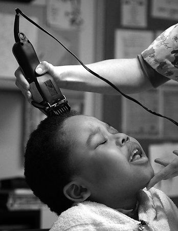 Third Place, Feature picture story - Michael E. Keating / MIchael E. KeatingJust like every kid, a haircut is a bit of a bother. Manny Evans, 7, has lived five of his seven years as a resident of Cincinnati Children's Hospital Medical Center.  Diagnosed with neurofibromatosis the genetic disorder that forms tumors that surround nerves, Manny  requires medical and nursing care beyond what can be provided in a residential environment.  His mother chooses to let him live at the hospital instead of a residential center or nursing home.  Manny recently began his schooling at Roselawn Condon School and a school bus picks him up each day in front of the hospital.  A fleet of nurses, personal attendants and caregivers provide the love and care, emotionally and physically, often the responsibility of a parent.  