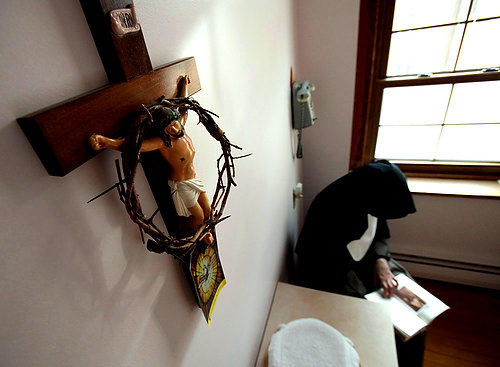 First Place, Feature Picture Story - Lisa DeJong / The Plain DealerThe Crown of Thorns, which is presented to a Sister when she takes her solemn vows, looks over Mother Dolores as she reads the poetry of her favorite poet, Robert Frost, inside her frugal "cell", her bedroom, inside her cloistered living quarters.