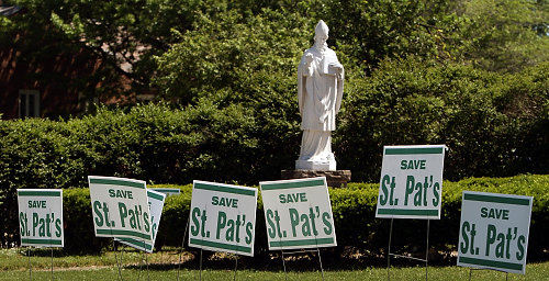 Second Place, News Picture Story - Gus Chan / The Plain DealerSave St. Pat's signs line the church property in front of a statue of St. Patrick during the closing of the church.  More than 300 people turned out to protest the bishop's final mass.  
