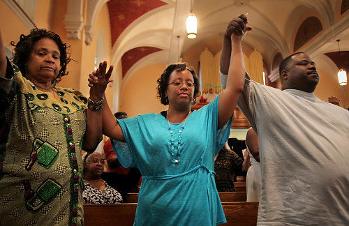 Second Place, News Picture Story - Gus Chan / The Plain DealerElayna Hodges, center,  holds hands while praying during the final mass at St. Adalbert Church.  St. Adalbert, home to Cleveland's oldest black Catholic congregation, closed it's doors Sunday morning as part of the diocesan downsizing. 