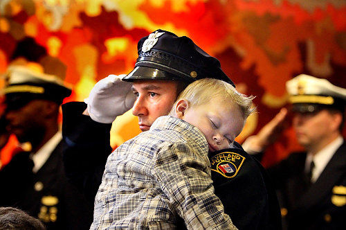 First Place, Photographer of the Year/Large Market - Lisa DeJong / The Plain DealerCleveland Detective David Shapiro holds his sleeping nephew, Brady Patsouras, 2, while saluting during 2010 Badge Case Ceremony at the police headquarters in downtown Cleveland.  Shapiro's father, Cleveland police officer William Shapiro, was killed in the line of duty on  April 26, 1974. William Shapiro was killed on his own birthday. The Cleveland Police Memorial Society honored fallen police officers during the annual badge ceremony which kicks off Cleveland's police memorial week. 