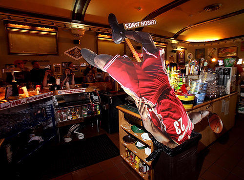First Place, Photographer of the Year/Large Market - Lisa DeJong / The Plain Dealer LeBron James seems already forgotten as bar patrons go back to life as usual after a waitress at The Winking Lizard in Lakewood threw this LeBron James life-size, stand-up poster into the trash after watching the Cleveland Cavaliers star announce he was going to the Miami Heat on ESPN.