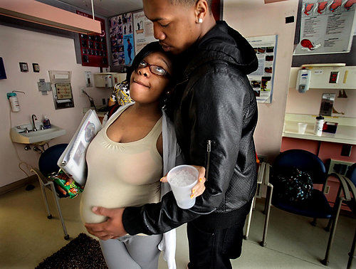 First Place, Photographer of the Year/Large Market - Lisa DeJong / The Plain DealerMarquis Robinson, 18, right, rubs the stomach of his pregnant girlfriend Alisha Ivey, 18, just after their support group during the new prenatal program called Centering Pregnancy at MacDonald Women's Hospital at University Hospitals. Robinson is determined to be a dedicated father and attends the classes with Ivey. She is 35 weeks pregnant with a boy they will name Marius. Centering Pregnancy encourage young fathers to be fully involved. They have group support sessions on nutrition, labor and birth preparation and coping skills. The program was started by nurse and midwife Pam Hetrick with a grant from Kaiser Permanente. 
