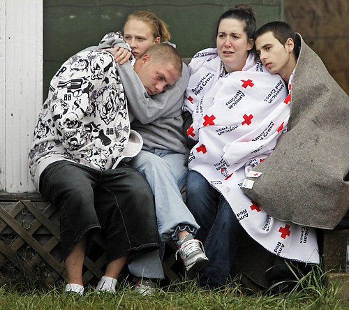 First Place, Spot News over 100,000 - Chris Russell / The Columbus DispatchJoey Climer, Brittany Canterbury, Emily Hedges and Jesse Climer (from left) huddle on a  porch watching Columbus firefighters working at the scene of a fatal fire that killed 3 people including the Climer's grandmother Deanna Perry.  