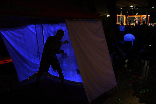 First Place, Sports Picture Story - Ed  Suba Jr / Akron Beacon JournalCaged Madness is an amateur mixed martial arts show that is a combination boxing, kick-boxing, submission-style wrestling and karate blended together in an eight-sided cage. It's part ruthless aggression and part disciplined art. It oozes machismo but seems to have a soul all at the same time. Where else can you see a man bloody someone's face before choking him out with his own arm, only to invite him to train together five minutes later? Some fans are young, some are old. Some women are stylish, others are comfortable in a T-shirt. Some men remain reserved, others yell to ''rip someone's head off.'' Some of the women in the crowd might yell that, too. A competitor shadow boxes as he prepares for his match during Caged Madness, an amateur mixed martial arts event.