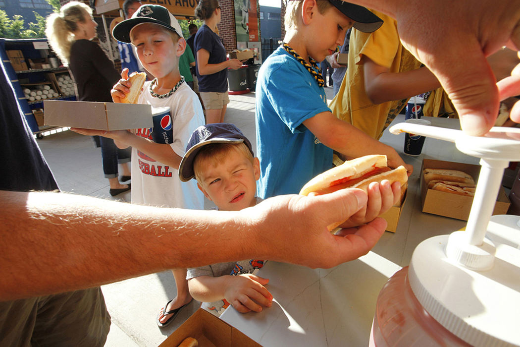 Second place, Feature - Brooke LaValley / The Columbus DispatchAaron Sullivan helps his dad Chris Sullivan apply the ketchup while his brother Ryan Sullivan (in the green and white hat), 8, takes a bite and his other brother Connor Sullivan, 10, helps garnish the rest of the dogs during dime a dog night at Huntington Park in Columbus. The Columbus Clippers were playing the Charlotte Knights, the family (all 4 boys and their dad Chris along with their mother, Shellie) had traveled from their home in Bexley to watch the game.  