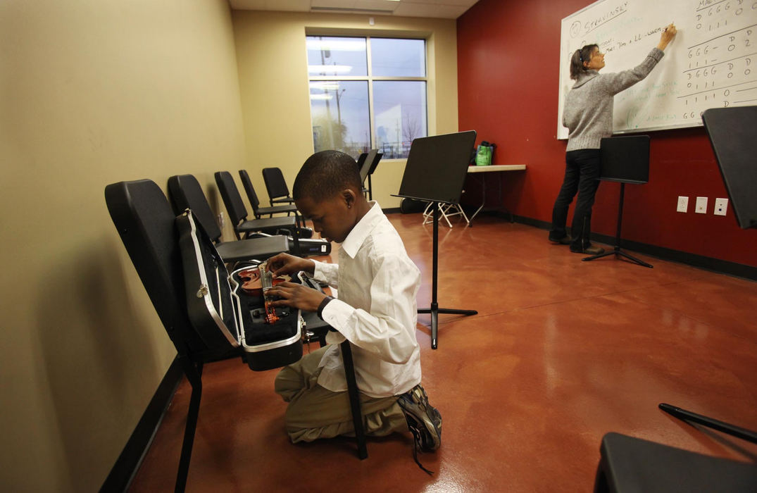 Second place, Feature Picture Story - Gus Chan / The Plain DealerIsaac Neal tunes his violin before El Sistema @ Rainey while teacher Isabel Trautwein writes the day's lesson on the board.  Neal is one of the older students in class and one of it's most talented.  He will attend Interlochen this summer to study violin.