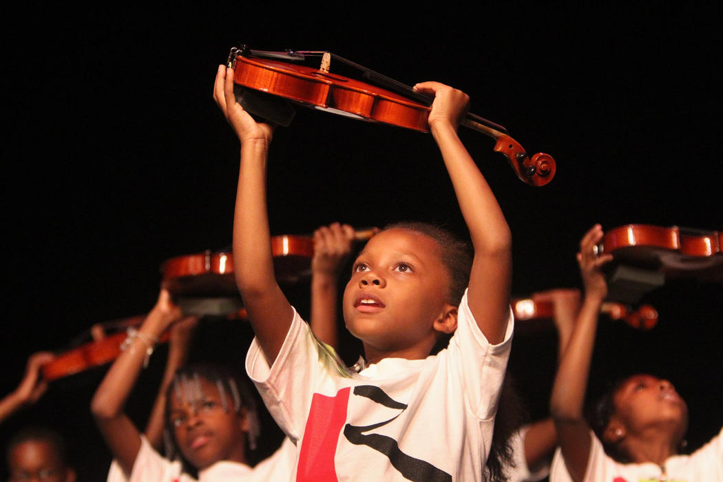 Second place, Feature Picture Story - Gus Chan / The Plain DealerMaiLonnie Walton participates in the violin up chant in preparation for positioning the violin during the Paper Violin Graduation Ceremony and Concert.  The young musicians received their real violins during the ceremony.  