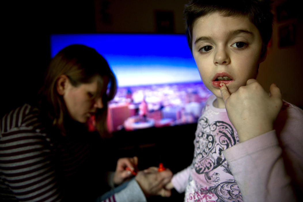 First place, Feature Picture Story - Abigail S. Fisher / Ohio UniversityAkeyna gives Angel a mini-manicure and paints her nails a bright orange. Angel, who has autism, is often overlooked in a household of four young children and wants to be a part of everything her siblings do.