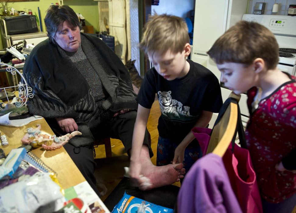 First place, Feature Picture Story - Abigail S. Fisher / Ohio UniversityAaron helps wash Pam's feet one afternoon after Akeyna and her children unexpectedly moved out of the house. Pam's health issues make caring for two young children a challenge.