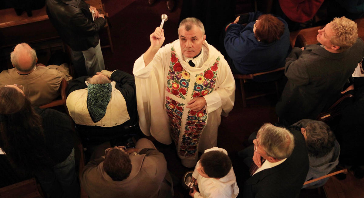 First place, News Picture Story - Gus Chan / The Plain DealerFr. Sandor Siklodi blesses the people with holy water during the reopening mass of St. Emeric Catholic Church.  Siklodi, the former pastor of the church, was brought back from Chicago to shepherd the church.  St. Emeric is the final church to reopen.  