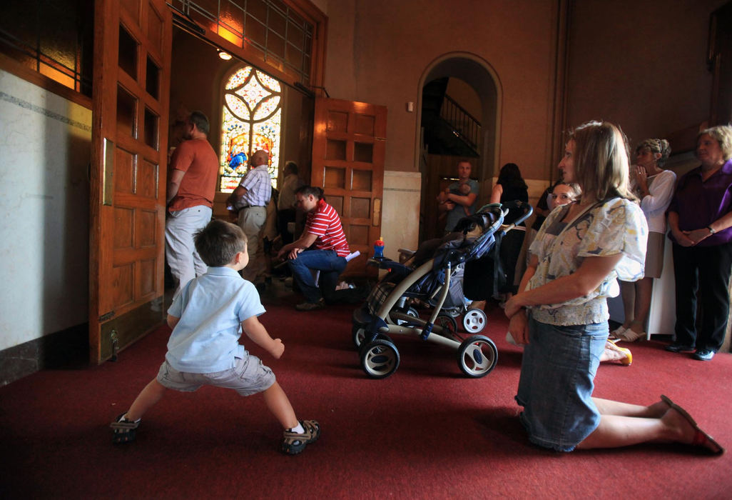 First place, News Picture Story - Gus Chan / The Plain DealerZaneta Haikal kneels in the foyer outside a packed St. Casmir sanctuary, as her son, Sebastian, 3, plays.  A capacity crowd turned out for the reopening mass.