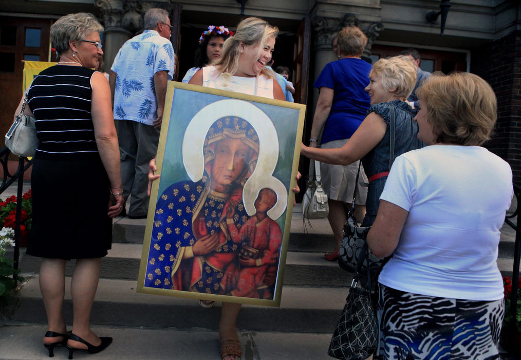 First place, News Picture Story - Gus Chan / The Plain DealerKristina Moreno carries a portrait of the Black Madonna that was part of the procession for the reopening mass of St. Casimir Catholic Church.  Moreno carried the portrait out of the church when it was closed and brought it back for the church's reopening.
