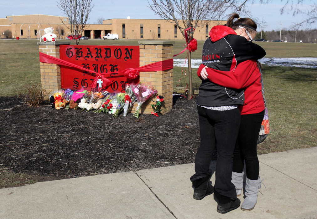 Second place, News Picture Story - Marvin Fong / The Plain DealerStudent T.J. Lane shot and killed three students and injured three others.  The violent incident shocked the small town of Chardon, OH.  The community unified through the experience and refused to let the shootings define them. Chardon High School juniors Halle Tierney, left, and Maddy McCluskey, right, console each other outside the school where shootings took the lives of 3 students and injured three others.    