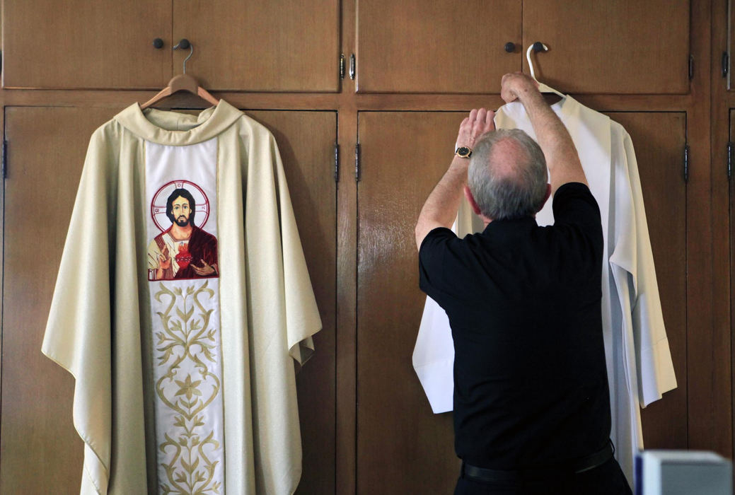 First place, News Picture Story - Gus Chan / The Plain DealerFr. James Ols puts on his vestments before the reopening mass of St. Patrick Catholic Church.  St. Patrick was one of three churches to open Sunday after the Vatican overturned Bishop Richard Lennon's order to close it. Ols returns to the parish where he grew up after serving 26 years at St. Vincent de Paul in Elyria.