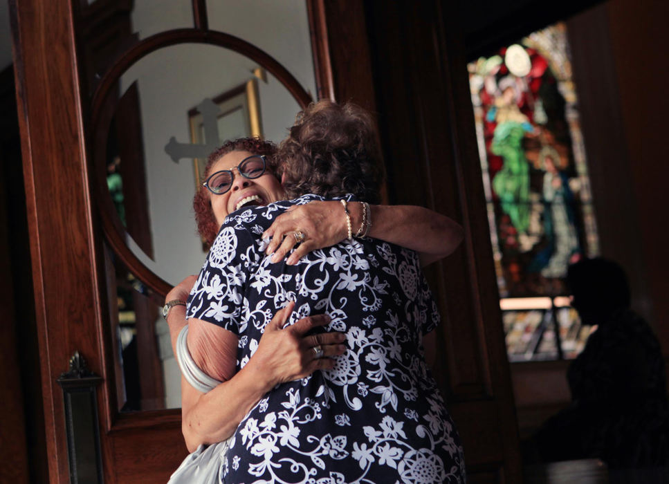First place, News Picture Story - Gus Chan / The Plain DealerLinda Gamble greets a longtime friend with a hug at the entrance of St. Adalbert Catholic Church before the reopening mass.  St. Adalbert is the city's oldest black Catholic congregation.  The reopening mass was the eighth of 11 churches to be reopened.  