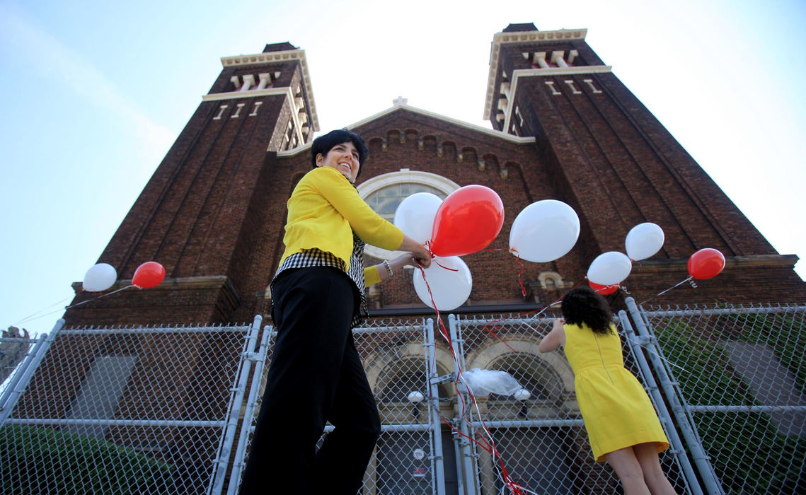 First place, Photographer of the Year - Large Market - Gus Chan / The Plain DealerColleen O'Shaughnessy, left, and her daughter, Kathleen tie balloons on the fence before the final vigil outside the closed St. Casimir Catholic Church.  The vigil marked the 140th consecutive Sunday outside the church since the closing on November 8, 2009.